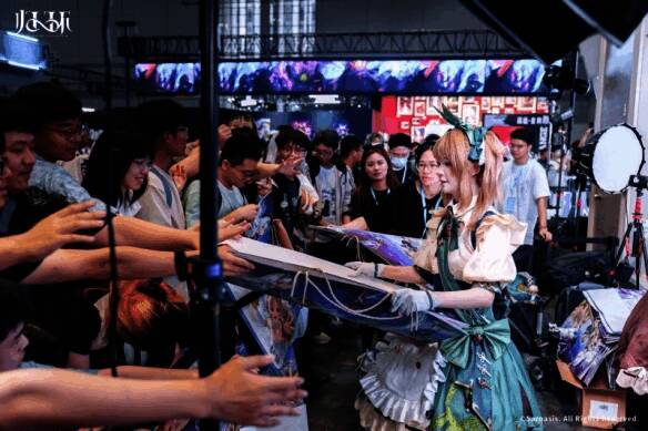 玩家在《归环》展区排队领取周边礼品，工作人员正在发放印有游戏角色形象的纪念袋