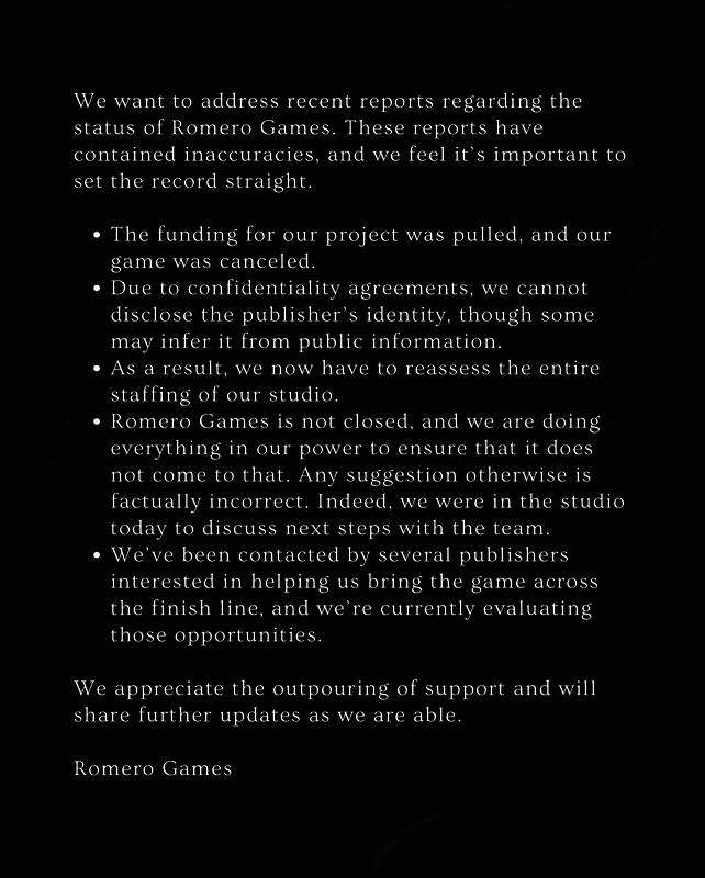 John Romero手持游戏原型设计图，背景为工作室内部环境