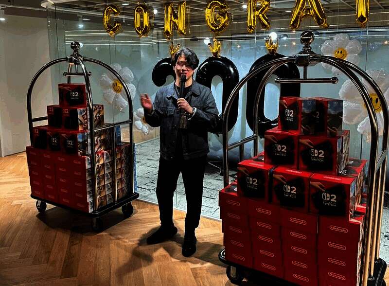 员工领取Switch2的现场画面，众人面带笑容搬运箱子