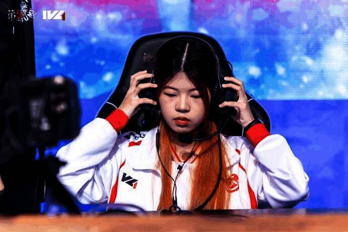 GG_violet在比赛中专注操作，神情认真，身后是战队成员的欢笑身影