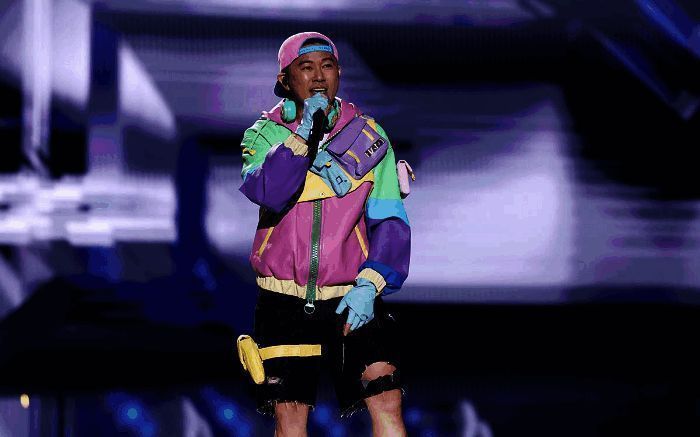 欧阳靖与豪华跑车同台表演，背景火焰特效烘托出激烈氛围