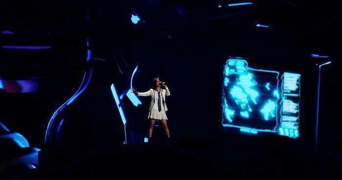 姚安娜与数字代言人吉莉同台表演，背景为未来感十足的虚拟舞台