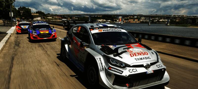 WRC赛车游戏宣传画面，多辆拉力赛车疾驰在泥泞山道上，车轮溅起大量泥土