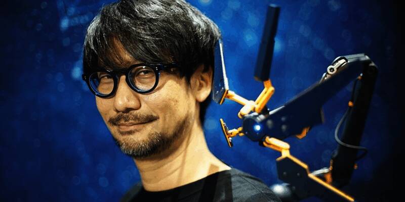 小岛秀夫在戛纳座谈会现场发言，神情专注，背景为科技感十足的屏幕展示