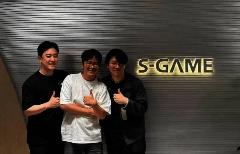 梁其伟在灵游坊办公室内与金亨泰交流画面，背景可见多幅原创角色插画