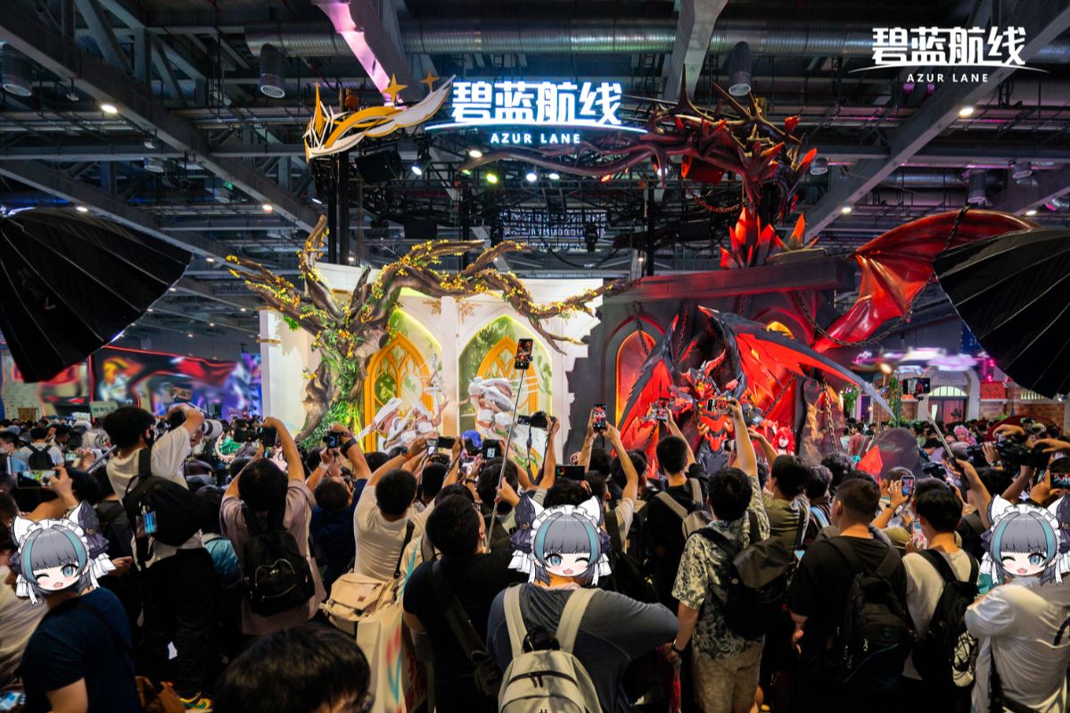 金狮Coser身穿精致舰装站在展台中央，周围粉丝举手机拍摄，笑容灿烂