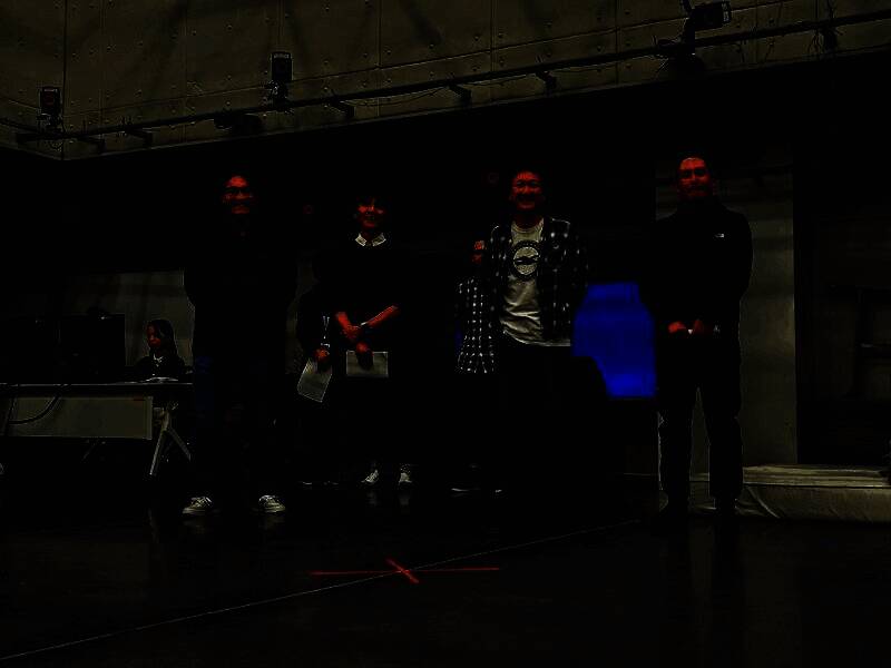 开发团队合影于动捕工作室门前，背景可见《怪物猎人：荒野》LOGO