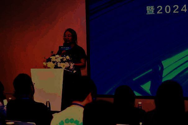 李婧在台上发表演讲，背景PPT展示行业安全挑战与标准意义