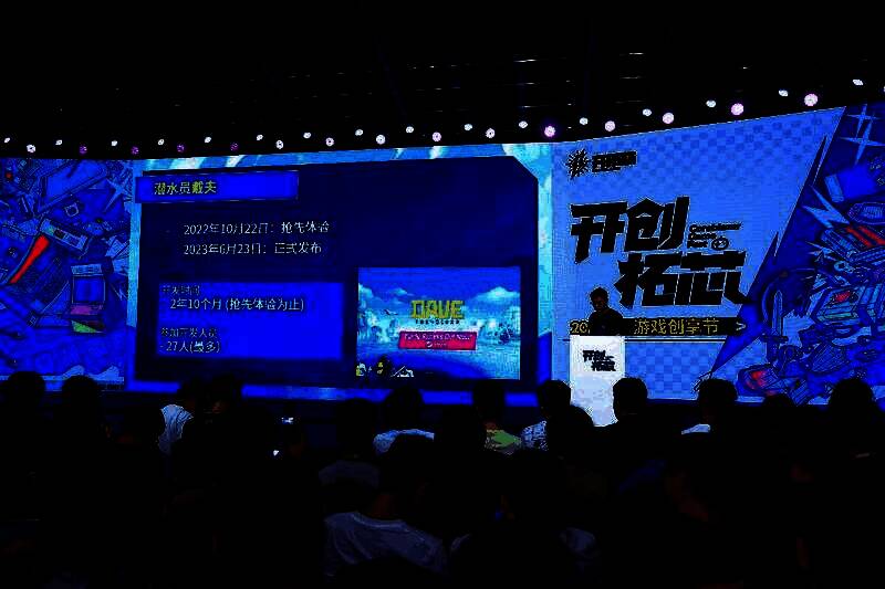 海猫络合物站在舞台中央演讲，背景为明日方舟LOGO和活动主视觉