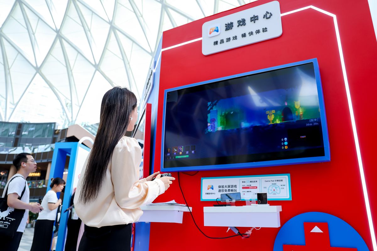 展台展示区陈列着多款游戏定制主题界面，观众正在体验个性化表盘设置