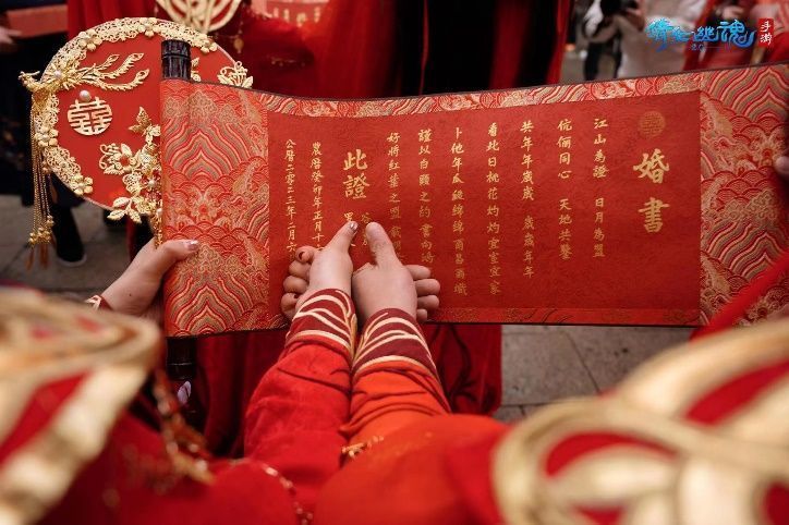 新人手持定制婚书与coser合影，背景为游园会互动摊位，气氛温馨欢乐