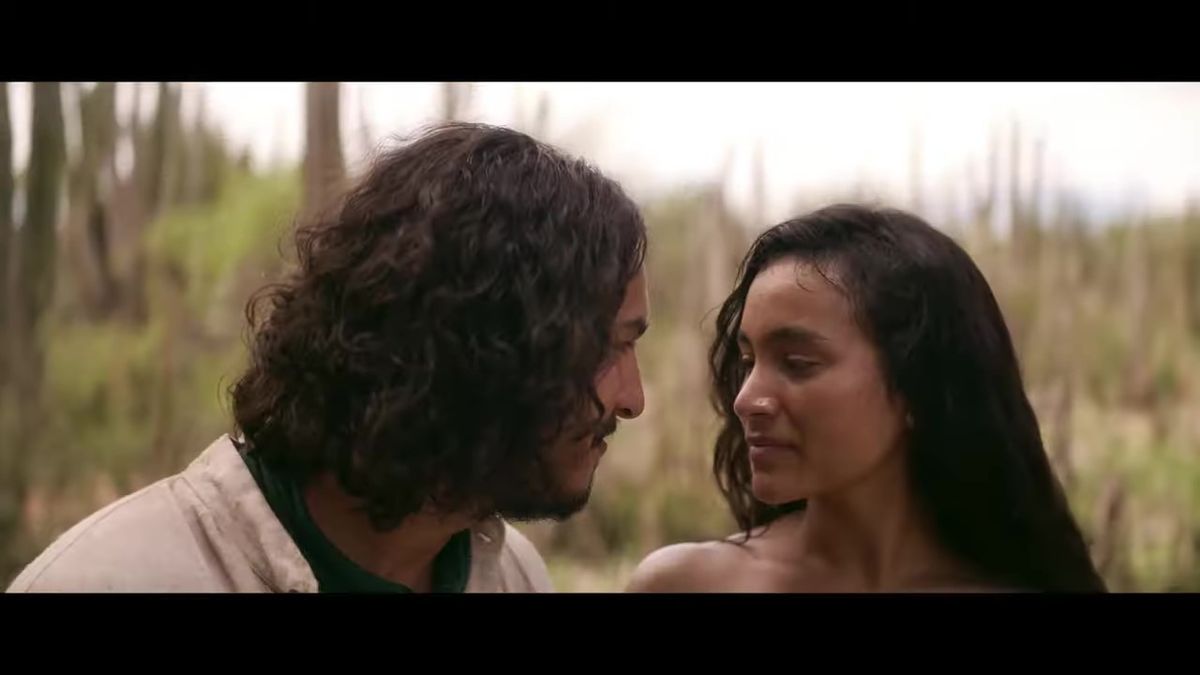 女子站在阳台眺望远方，风吹起她的长发和裙摆，背景是黄昏下的小镇