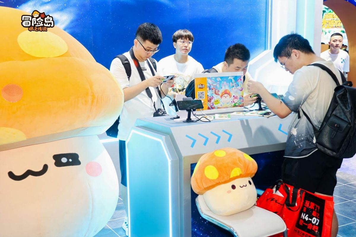 玩家在舞台上参与互动游戏，台下观众鼓掌助威，背景是《冒险岛：枫之传说》主题展板