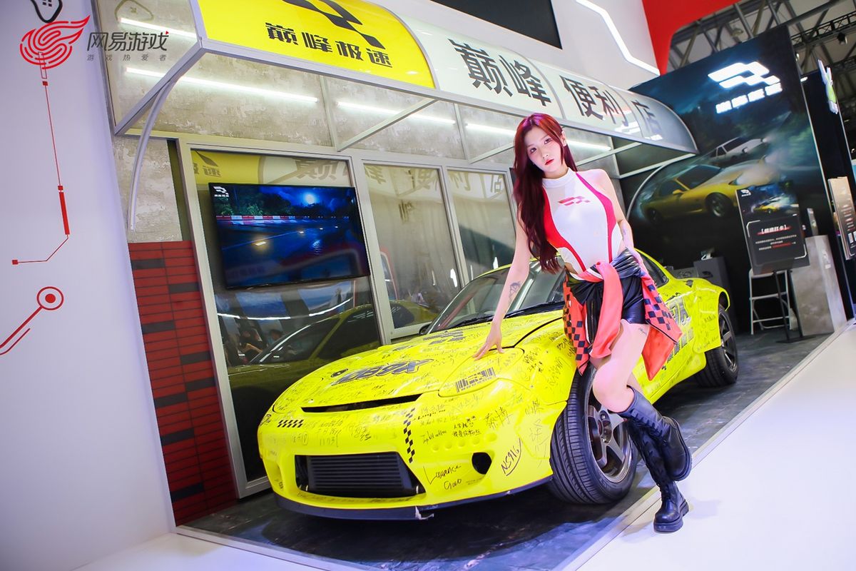 《巅峰极速》展区玩家与赛车和便利店装置合影，现场气氛热烈