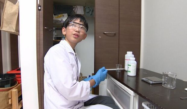 12岁少年今村建太身穿白大褂面对镜头，神情专注，背景为实验室环境
