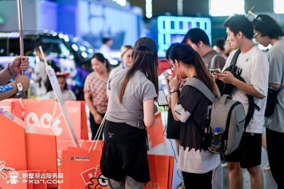 玩家正在参与互动游戏，展台工作人员在一旁引导，气氛活跃