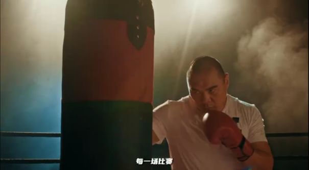 宣传片截图，张志磊站在擂台中央发表演讲，身后大屏幕播放《荒野迷城》游戏画面