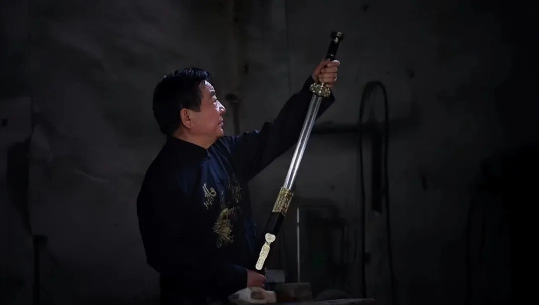 高庆民在工作坊内指导弟子锻剑，背景陈列多把已完成的棠溪宝剑