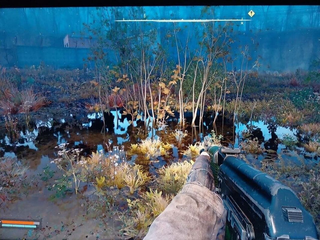 开阔的废弃小镇场景，远处有倒塌的塔吊和冒烟的残骸，天空呈现灰黄色调