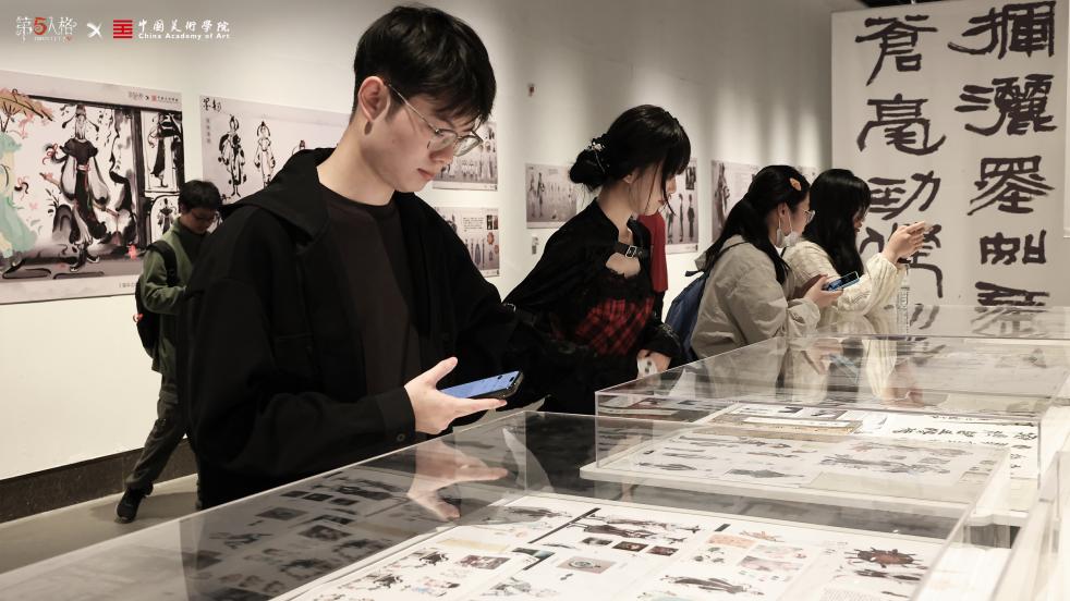 观众近距离观看《宿伞之魂》主题设计，作品融入水墨晕染与行书笔意