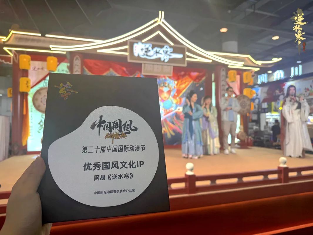 《逆水寒》团队在动漫节领奖现场，手持‘优秀国风文化IP’奖杯，背景为展台国风装饰