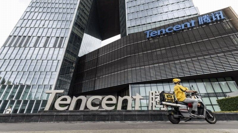 腾讯首席战略官詹姆斯・米歇尔在Q3业绩会上发言的现场照片，背景为腾讯财报数据图表