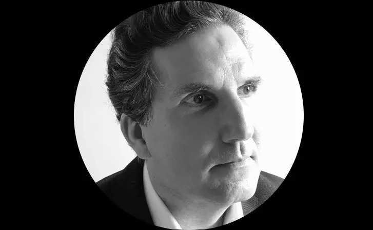 Sébastien Froidefond 官方肖像照，背景为育碧公司标志，神情严肃展现专业气质