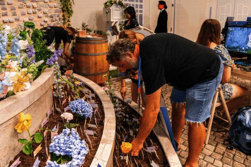 玩家在《无限暖暖》展台参与种植互动，屏幕上显示虚拟花园生长过程