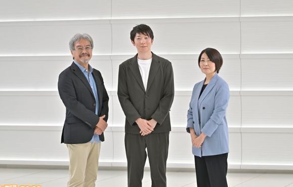 开发团队工作场景，青沼英二与佐野友美正在讨论游戏设计图纸，桌上摆满角色草图与关卡模型