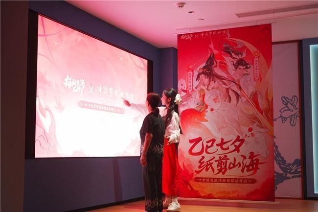 扬州剪纸传承人张震梅与国风博主苏久承共同创作《指间山海》角色剪纸，两人专注雕刻，桌上摆放着已完成的嫦娥剪纸作品