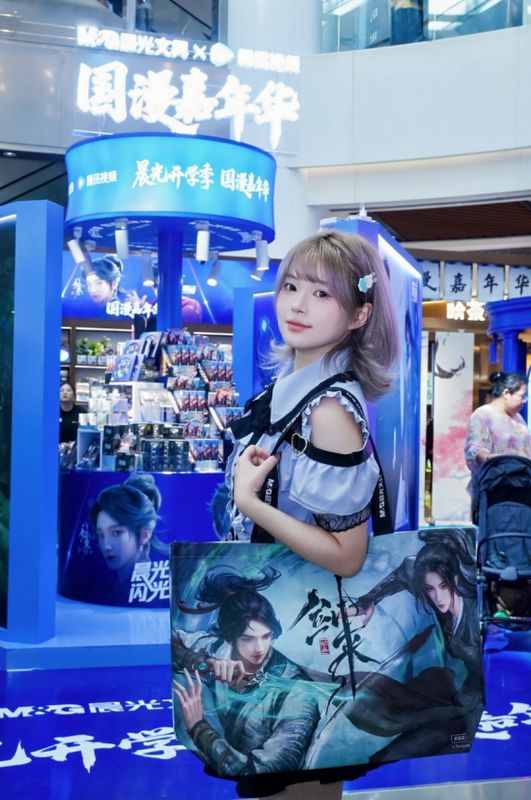 粉丝手持萌粒笔与COSER合影，背景为《剑来》主题场景