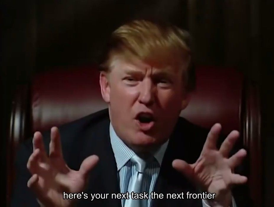 特朗普身穿深色西装站在E3展台中央，手持Xbox手柄面向镜头讲话