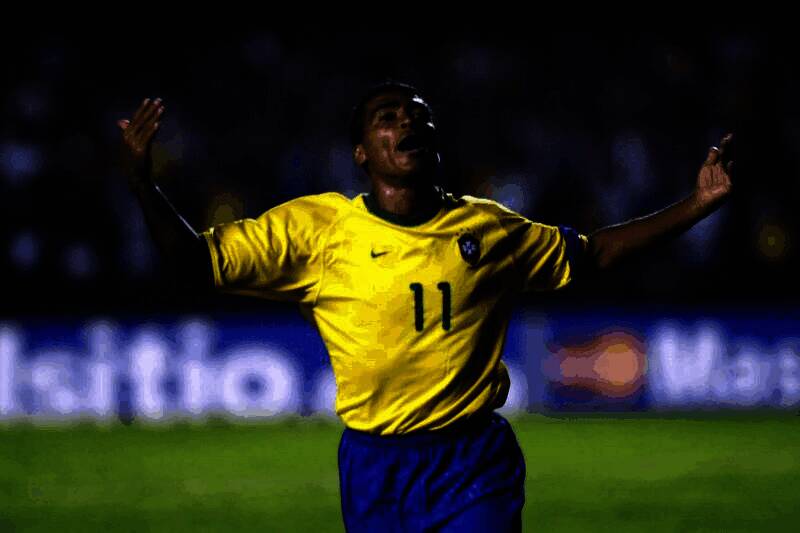 罗马里奥身穿巴西国家队球衣，摆出标志性庆祝动作，背景为绿茵赛场与欢呼球迷