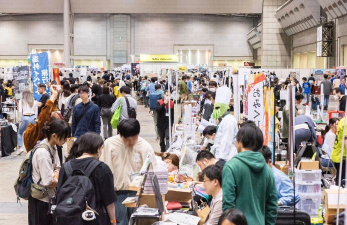 展台前人头攒动，观众正在翻阅桌游说明书并与开发者交流玩法细节