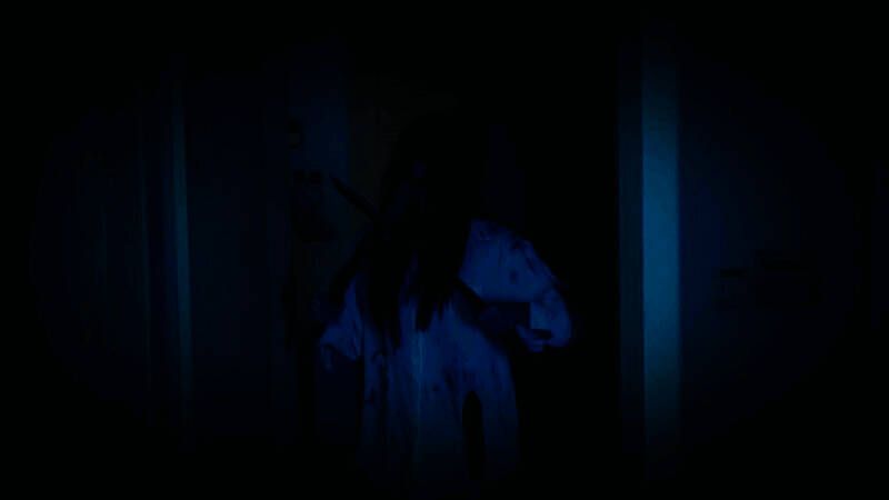 女主角站在镜子前，镜中映出扭曲人脸，背后阴影中有模糊人形