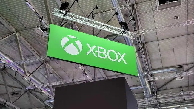 Xbox主机与手柄摆放场景，背景显示多款热门游戏封面拼接