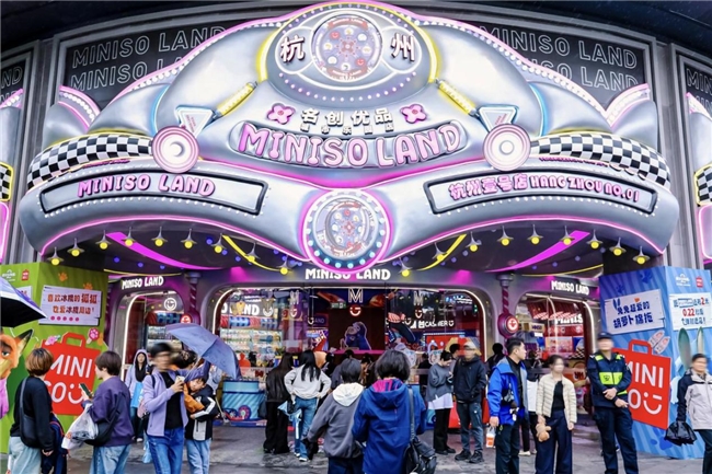 名创优品MINISO LAND杭州店外景全景，建筑外观现代时尚，人流如织，门前设有《疯狂动物城2》主题装饰