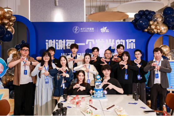 不董事会成员在光子工作室合影，背景为巨型游戏LOGO墙，众人手持定制工牌笑容满面
