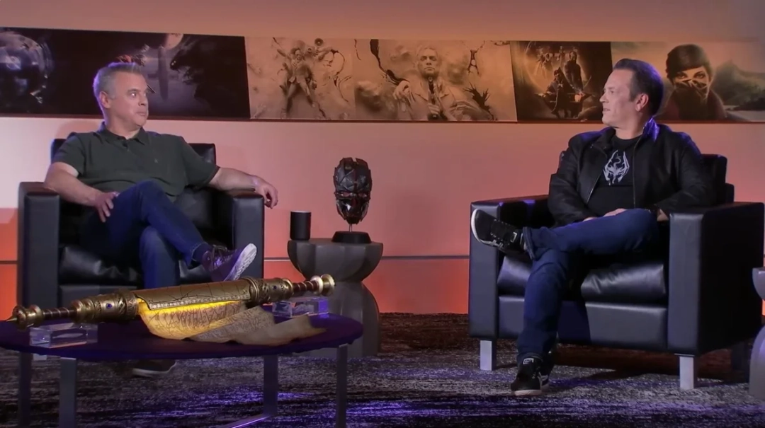 皮特·海恩斯在E3展台激情介绍新作的黑白历史影像，背景大屏显示《上古卷轴V：天际》标志性龙吼画面，台下观众举着手绘B社LOGO灯牌